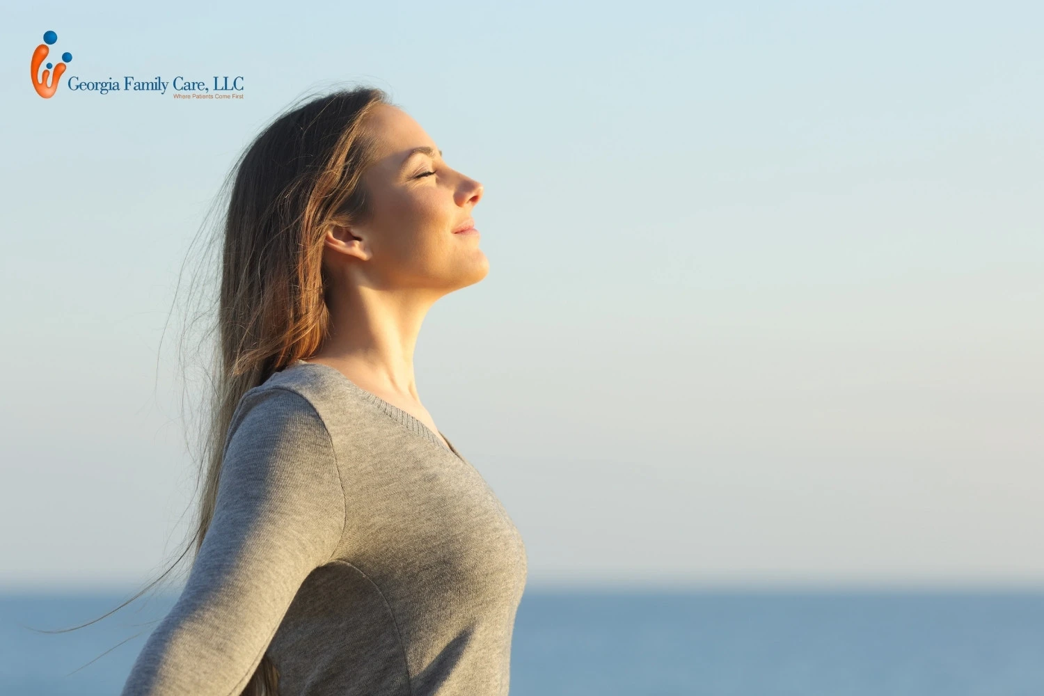 A woman practicing deep breathing by the sea, symbolizing relaxation and mental health healing, from GA Family Care.