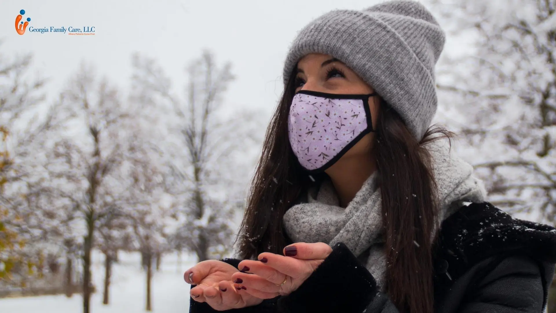 Woman wearing a mask and winter clothing outdoors during snowfall, representing cold weather safety and health protection recommended by Georgia Family Care.